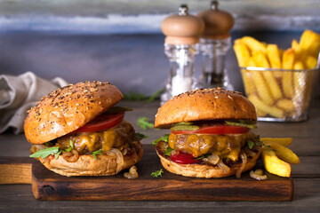 Beef burger in classic american style with hot grilled patty, melted cheese on top, tomato, onion, sauce and chips