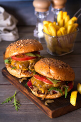 Beef burger in classic american style with hot grilled patty, melted cheese on top, tomato, onion, sauce and chips