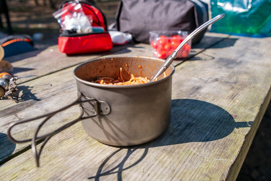 Cooked vermicelli with tomato paste during a picnic in a metal pot