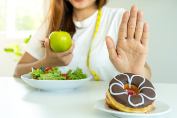 Diet concept. Healthy women use hands to reject unhealthy foods such as donuts or desserts. Slim women choose healthy foods and high vitamins, such as apples and vegetable salads.