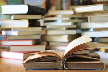 A close up shot of an old book open on the library desk A pile of books in the background selective focus and shallow depth of field