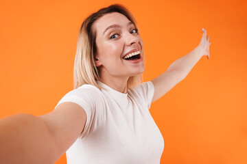 Image of excited cute woman smiling while taking selfie photo