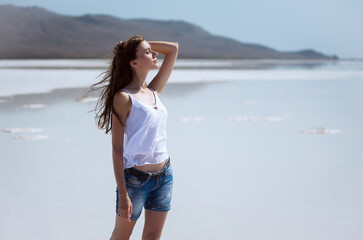 Young beautiful girl on a dry salt lake in the summer at noon