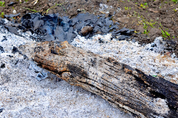 Fototapeta na wymiar Ashes from the fire, a half-burned piece of log with a charred edge close-up.
