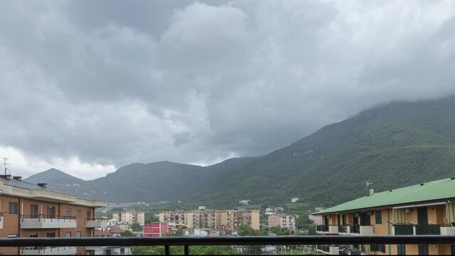 Angri, Italy. Timelapse of clouds gathering with rain showers on a residential area with a mountain in the background. Beginning and end of a thunderstorm.