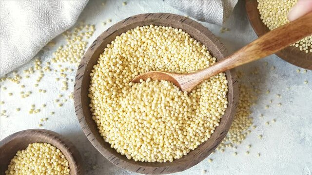 Raw dry hulled millet in a bowl with a spoon