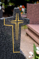 cross on a stone grave in a city cemetery