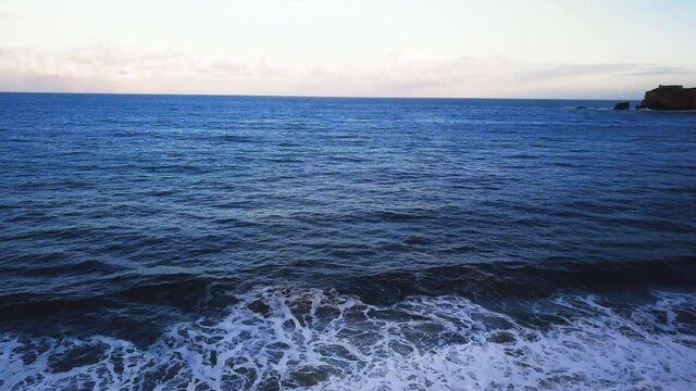 Flying over a sandy beach. Waves break on a sandy beach on the Atlantic coast, aerial View. Nazare, Portugal.