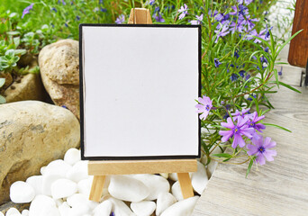 Little wooden tripod with blank canvas in a garden mock up