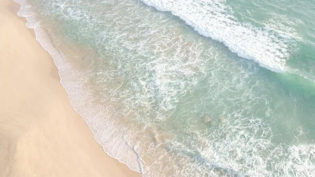 4K UHD aerial drone view top view waves crashing empty beach from above. Areal drone view moving beach.