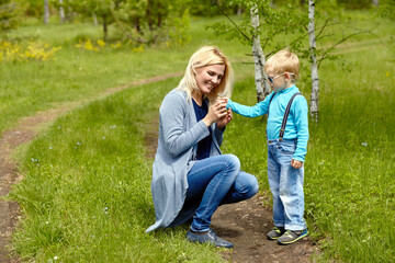 Fototapeta premium son giving flowers to his mother. child and mom walking.