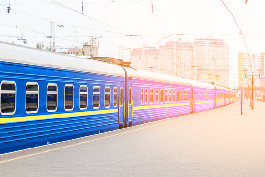 Blue local train at the railway station in the sunset sunlight. Train on a railway platform.