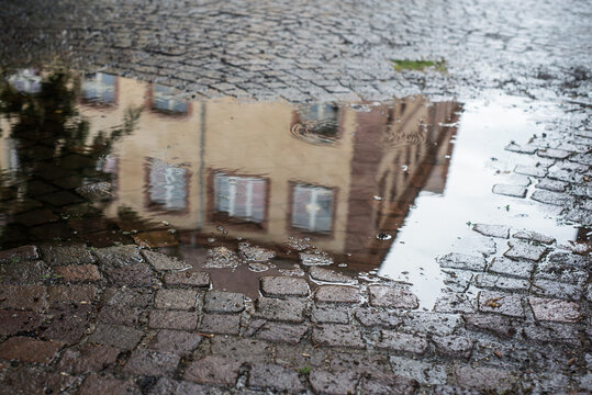 Closeup of historical building reflection in a pubble of water on cobblestone surface  in the street
