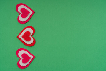 Vertical red hearts on a green background. Copy space.