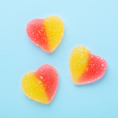 Colorful gummy hearts on blue background. Jelly sweets. Top view. Square