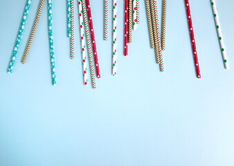 Drinking straws for party on blue pastel background with copy space. Top view of colorful paper disposable eco-friendly straws for summer cocktails.