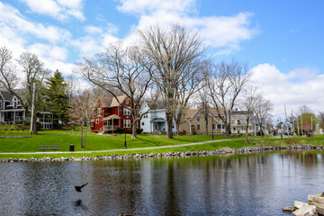 Row of buildings reflect in water along shore of inlet in Sydney, Nova Scotia. 