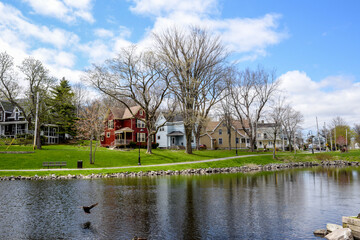 Row of buildings reflect in water along shore of inlet in Sydney, Nova Scotia. 