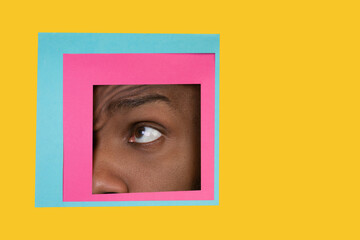 Asking. Eye of emotional african-american man peeks throught square in yellow background. Trendy geometrical style, copyspace. Vibrant colors. Sales, proposal, finance and business concept.