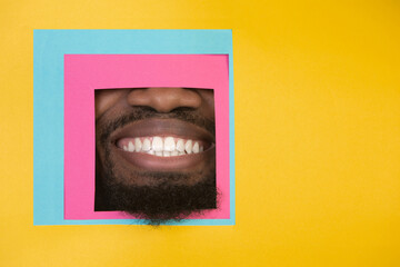 Smile. Mouth of emotional african-american man peeks throught square in yellow background. Trendy geometrical style, copyspace. Vibrant colors. Sales, proposal, finance and business concept. Framing.