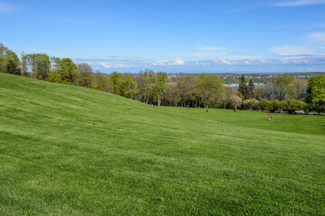 Rolling grassy hills in Battlefields Park with blue sky and a view overlooking Quebec, Canada.