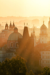 View of foggy Prague with Charles Bridge from Petrin hill view point in the early morning with sun rays coming through the fog. Silhouettes of temples, towers and buildings. Prague, Czech Republic.