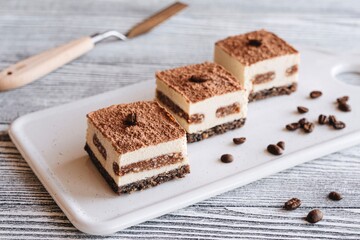 Tiramisu cakes and coffee beans on a wooden white background