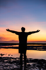 Fototapeta premium Silhouette of a man enjoying a beautiful sunrise
