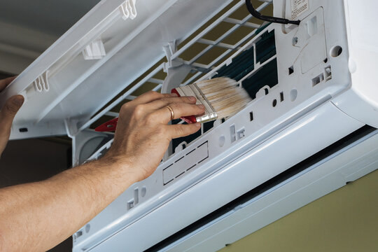 A man cleans the filter of a household air conditioner. Cleaning of premises.Hand close up