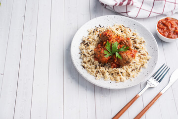 Beef meatballs and brown rice on a plate. Ready made portioned dish meat with garnish. Copy space.