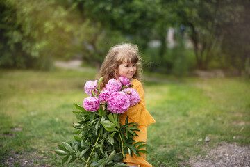 Little girl is playing in the park. The child is walking. Summer rest. Long haired blonde smiles.Beautiful baby with peonies. Girl with a bouquet of flowers