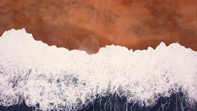 Flying over a sandy beach. Waves break on a sandy beach on the Atlantic coast, aerial View. Nazare, Portugal.
