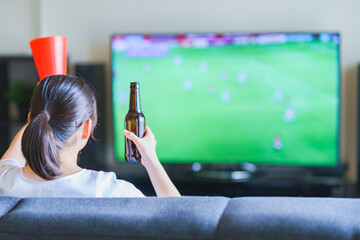 家でスポーツをテレビ観戦する若い女性のイメージ【プロサッカーの動画配信サービス】 © show999