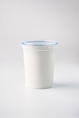 food photography of clean white sterile plastic jar of natural dairy product (sour cream) close-up on a light gray background isolated
