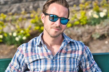 portrait of a trendy young man in the city sit on bench