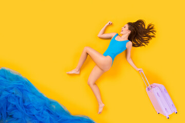 Full length high angle above flat lay view profile photo of beautiful lady seaside resort run into water with rolling suitcase can't wait wear bodysuit isolated yellow color background