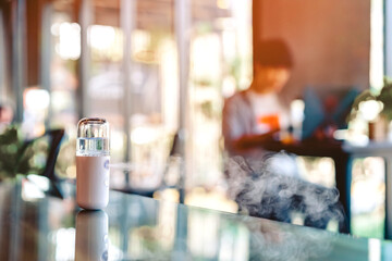 Alcohol nano mist sprayer for hand cleaning to prevent the spread of the corona virus (Covid-19) placed on the table to serve customers before buying in the coffee shop. Modern health technology.