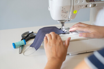 Hands on sewing machine making face make during corona virus