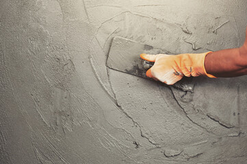 hand of worker plastering cement at wall for building house