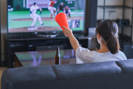 家でスポーツをテレビ観戦する若い女性のイメージ【プロ野球の動画配信サービス】
