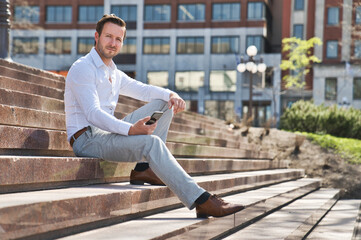 Obraz premium Portrait of an handsome man on the urban background holding phone