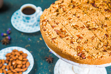 Cut cake on table with almonds and a cup of coffee. Baked dessert with chopped nuts in plate on table with coffee, piece of cake and almonds.