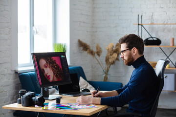 Retouching images in special program.Portrait of graphic designer working in office with...