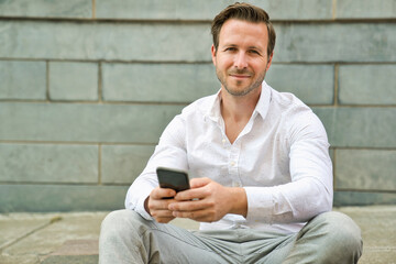 Obraz premium Portrait of an handsome man on the urban background holding phone