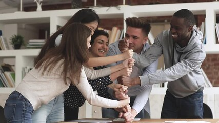 Happy united multiethnic college university students office business people stacking fists engaged in teambuilding motivated by success, team support help teamwork, international friendship concept