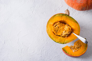 Ripe pumpkin cut into pieces, take out spoon of seeds. Healthy food. View from above. Copy space.