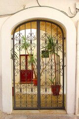 View at courtyard garden and patio behind arched wrought iron doors, Gallipoli, Apulia, Puglia, Italy 