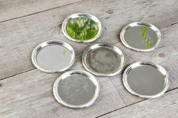 Antique silverplated coasters on wooden background.