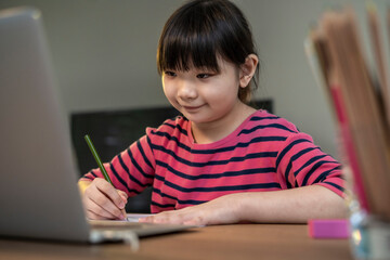 Asian girl student online learning in class study.Online video call with teacher.Child girl eating rice congee breakfast with laptop at home.New normal.Covid-19 coronavirus.Social distancing.stay home