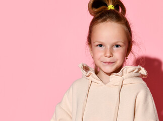Portrait of pretty little kid girl in stylish beige hoodie close up posing on pastel pink